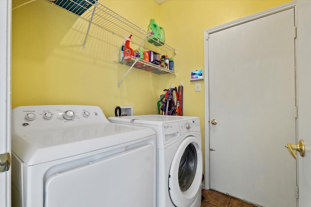 laundry area featuring washer and clothes dryer and dark tile patterned floors