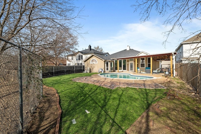 rear view of house with a lawn, a fenced in pool, ceiling fan, and a patio