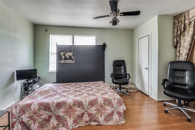 bedroom featuring ceiling fan, wood-type flooring, and a textured ceiling