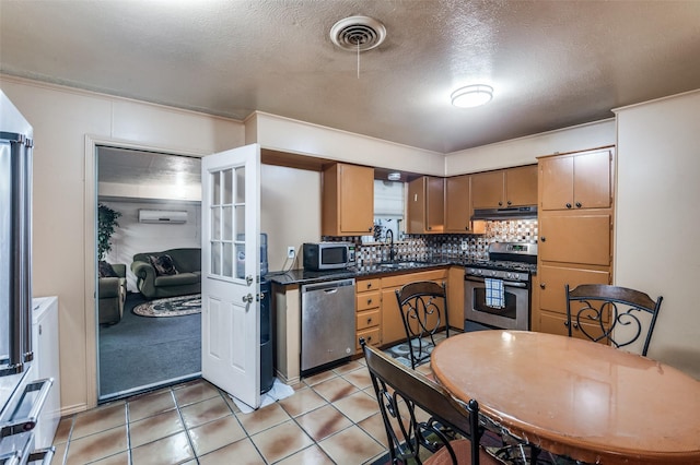 kitchen with appliances with stainless steel finishes, decorative backsplash, a textured ceiling, an AC wall unit, and sink