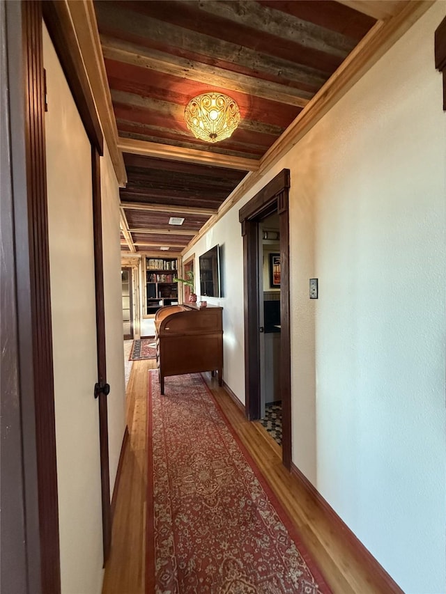 hall with wood-type flooring, wood ceiling, and ornamental molding