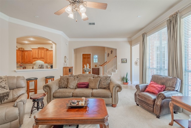 living room with ceiling fan, light carpet, and crown molding