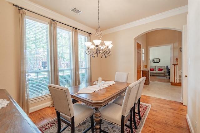 dining space featuring light wood-type flooring, an inviting chandelier, and ornamental molding