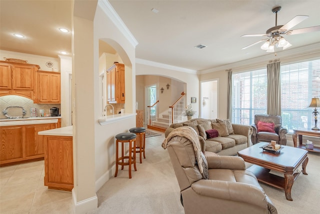 carpeted living room with ceiling fan and ornamental molding