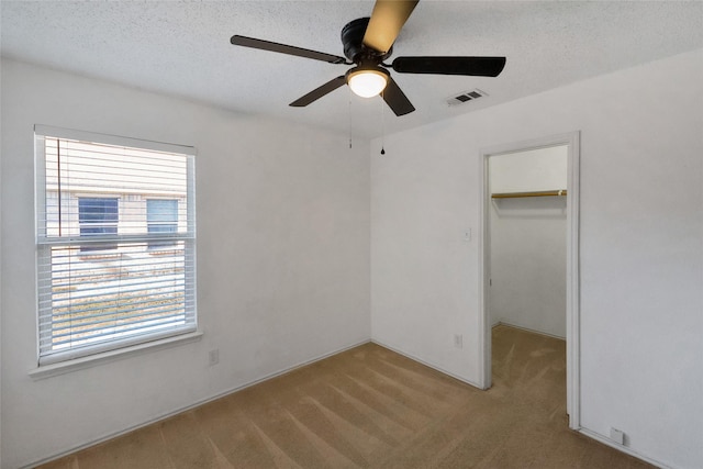 unfurnished bedroom featuring a spacious closet, ceiling fan, a closet, and multiple windows