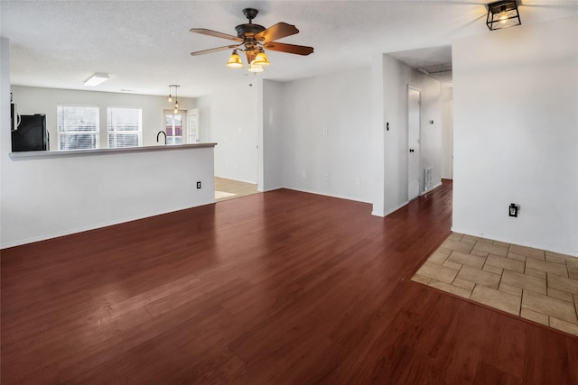 unfurnished living room featuring ceiling fan, dark wood-type flooring, sink, and a textured ceiling