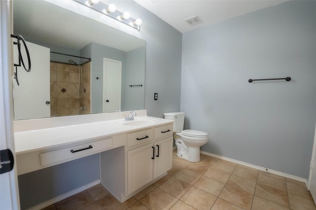 bathroom featuring toilet, vanity, a tile shower, and tile patterned flooring