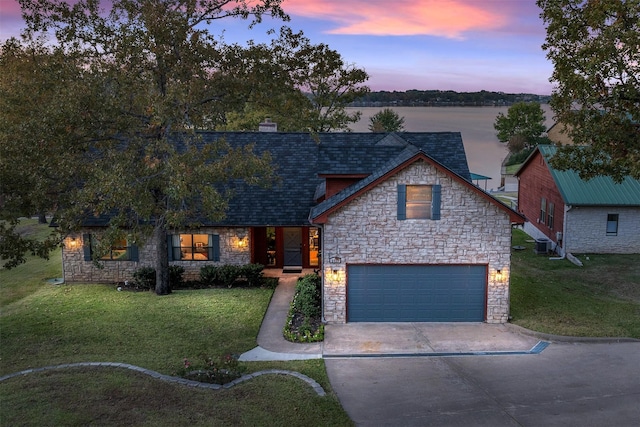 view of front of house with a water view, central AC, a lawn, and a garage