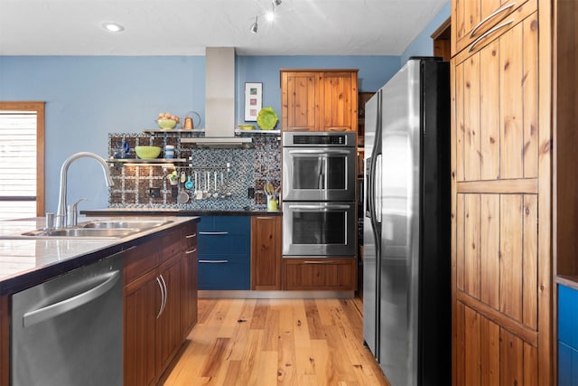 kitchen featuring decorative backsplash, sink, light wood-type flooring, stainless steel appliances, and wall chimney exhaust hood