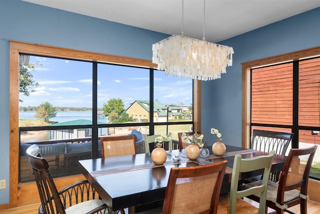 dining space featuring a water view, a healthy amount of sunlight, a notable chandelier, and hardwood / wood-style floors