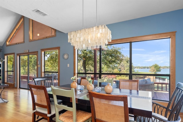 dining space with a water view, a chandelier, and hardwood / wood-style floors