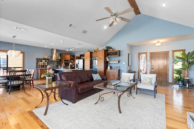 living room featuring ceiling fan, light hardwood / wood-style flooring, plenty of natural light, and high vaulted ceiling