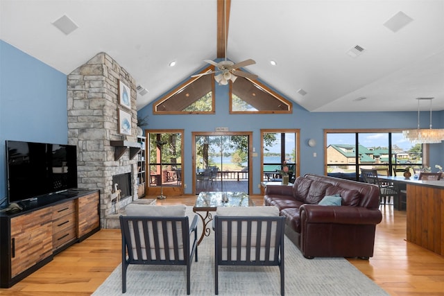 living room with vaulted ceiling with beams, a fireplace, ceiling fan with notable chandelier, and light hardwood / wood-style floors