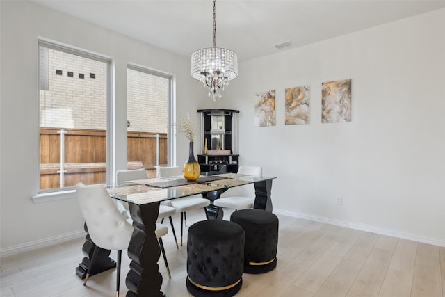 dining area with a chandelier, light hardwood / wood-style floors, and a wealth of natural light