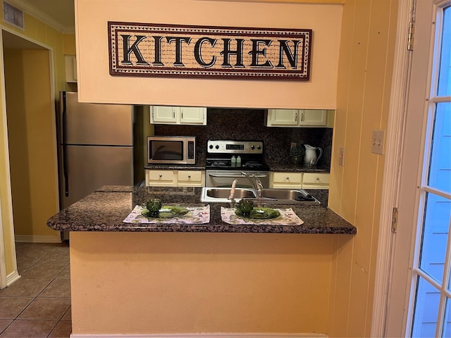 kitchen with dark tile patterned floors, kitchen peninsula, crown molding, and stainless steel appliances