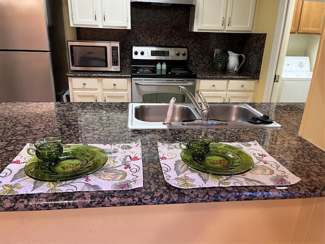 kitchen featuring backsplash, extractor fan, washer / dryer, sink, and appliances with stainless steel finishes