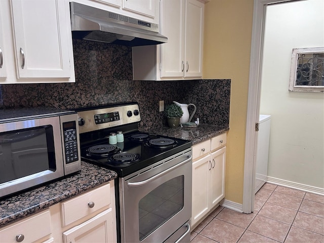 kitchen featuring backsplash, dark stone countertops, light tile patterned flooring, white cabinetry, and stainless steel appliances