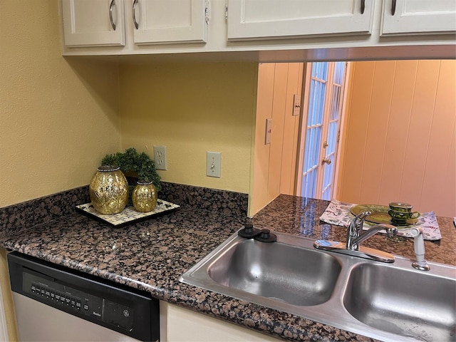 kitchen with dishwasher, sink, white cabinetry, and dark stone counters