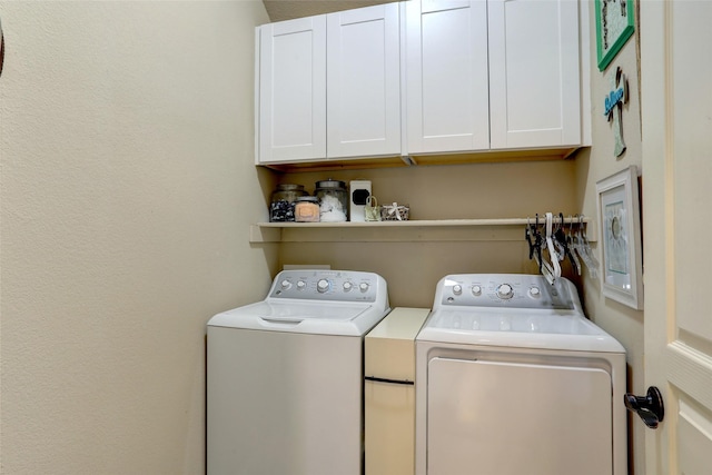 clothes washing area with separate washer and dryer and cabinets