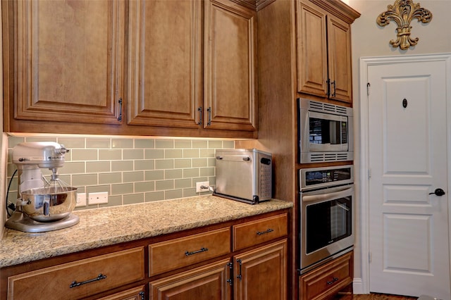 kitchen featuring light stone countertops, stainless steel appliances, and tasteful backsplash