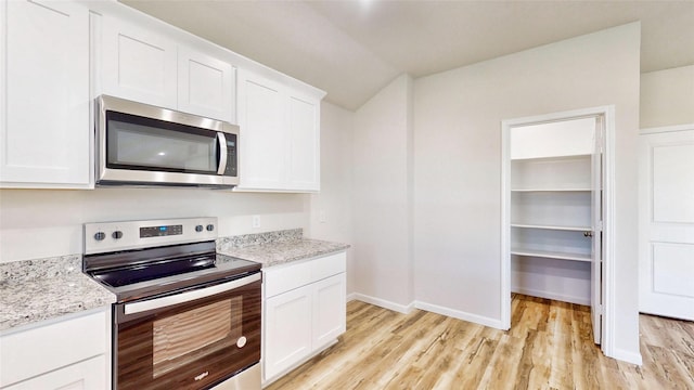 kitchen with stainless steel appliances, white cabinetry, and light stone counters