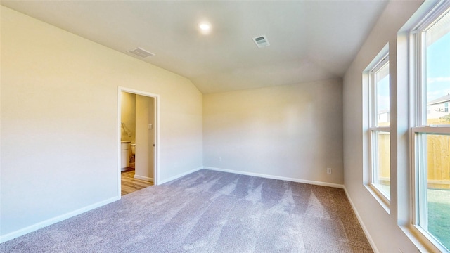 unfurnished room featuring light carpet and vaulted ceiling