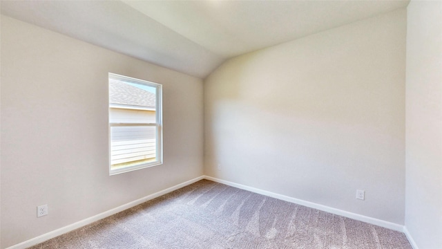 carpeted spare room featuring lofted ceiling