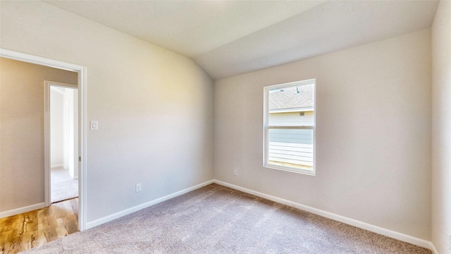 carpeted spare room with lofted ceiling