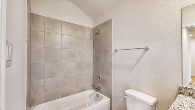 full bathroom featuring toilet, vanity, tiled shower / bath, and vaulted ceiling