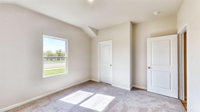 unfurnished bedroom featuring vaulted ceiling and light colored carpet