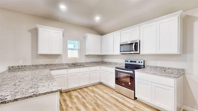 kitchen with appliances with stainless steel finishes, sink, white cabinetry, and light hardwood / wood-style flooring