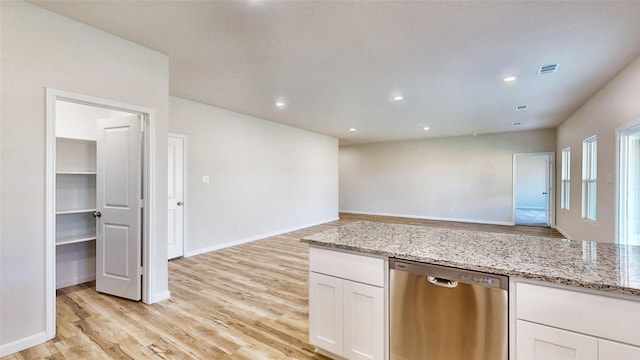 kitchen with light wood-type flooring, white cabinetry, stainless steel dishwasher, and light stone counters