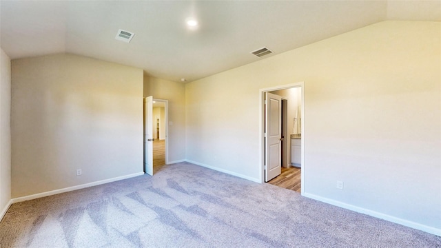 spare room with light carpet and lofted ceiling