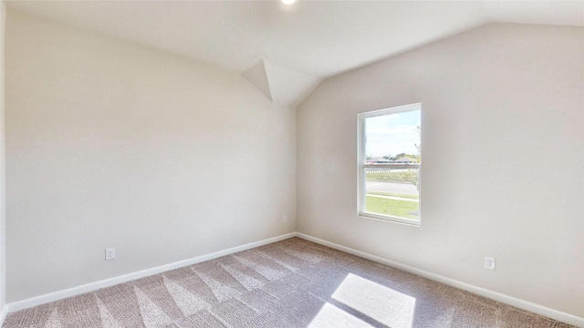 unfurnished room with vaulted ceiling and carpet flooring