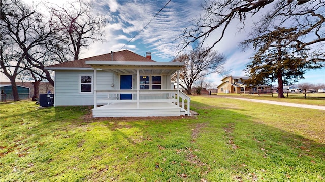 rear view of house featuring a lawn, central AC unit, and a porch