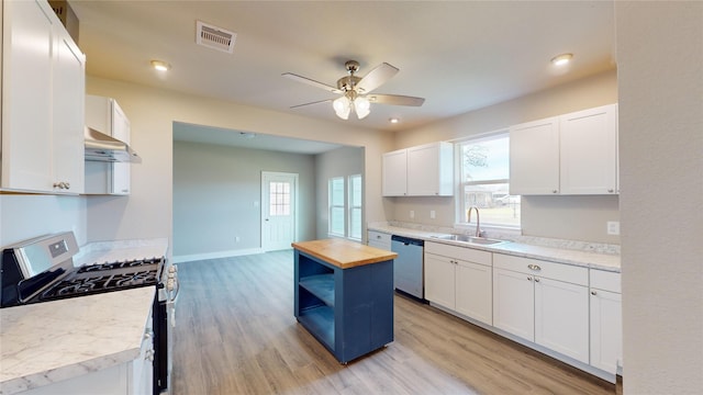 kitchen with a kitchen island, sink, appliances with stainless steel finishes, white cabinets, and wood counters