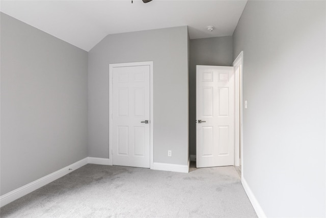 unfurnished bedroom featuring vaulted ceiling and light colored carpet