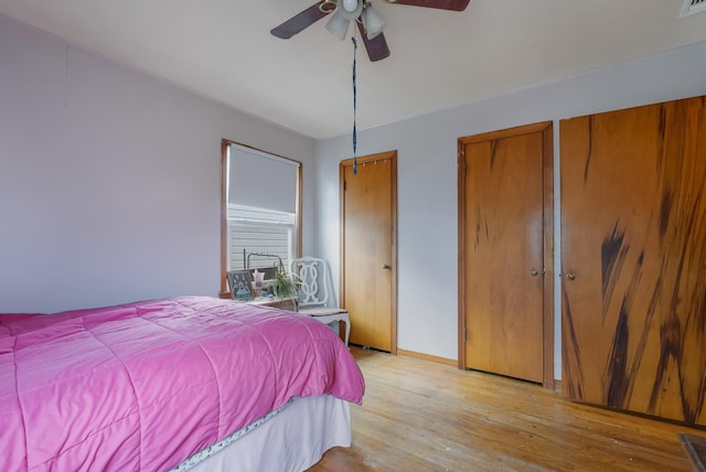 bedroom with ceiling fan, multiple closets, and light wood-type flooring