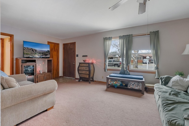 carpeted living area with ceiling fan and baseboards