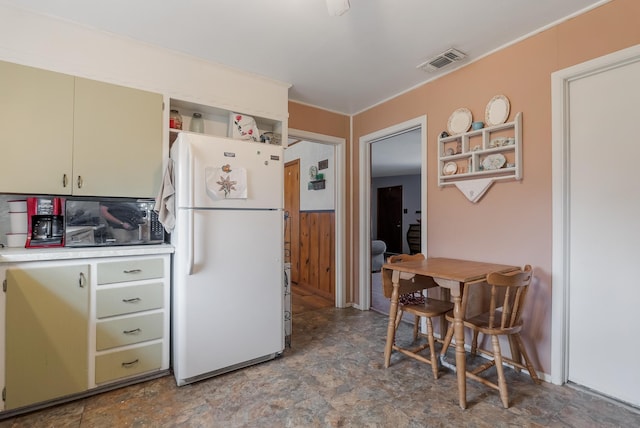 kitchen with green cabinets, white refrigerator, and wood walls