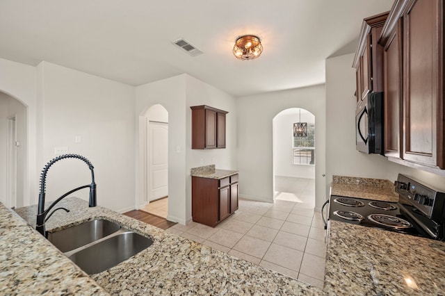 kitchen with black appliances, light stone countertops, sink, and light tile patterned flooring