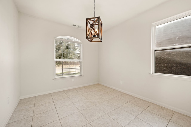 empty room featuring an inviting chandelier and light tile patterned flooring