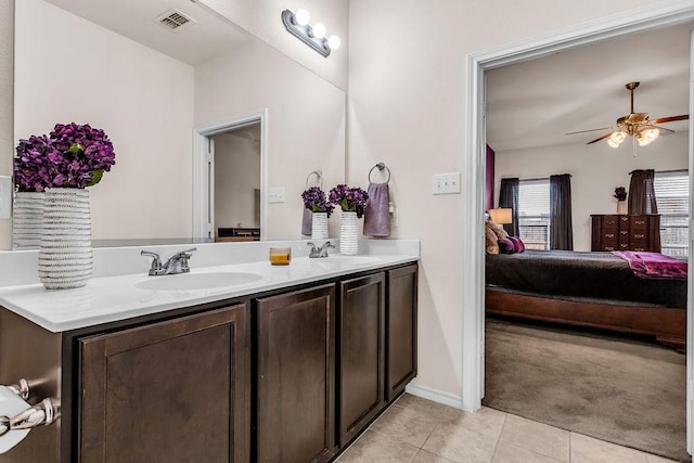 ensuite bathroom with tile patterned flooring, double vanity, ceiling fan, and baseboards