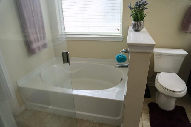 full bath featuring tile patterned flooring, toilet, and a bath