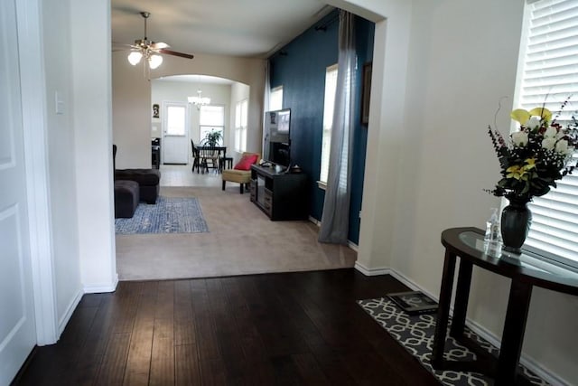 hall with arched walkways, a notable chandelier, baseboards, and hardwood / wood-style flooring