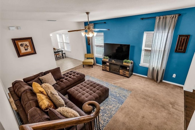 living area featuring arched walkways, a ceiling fan, and baseboards