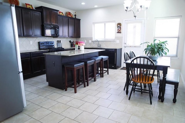 kitchen featuring black appliances, a kitchen island, decorative backsplash, and a sink