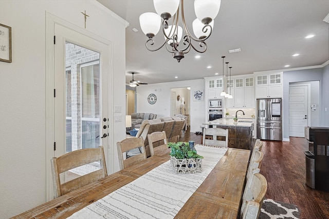 dining space featuring ceiling fan with notable chandelier, sink, dark hardwood / wood-style floors, and ornamental molding