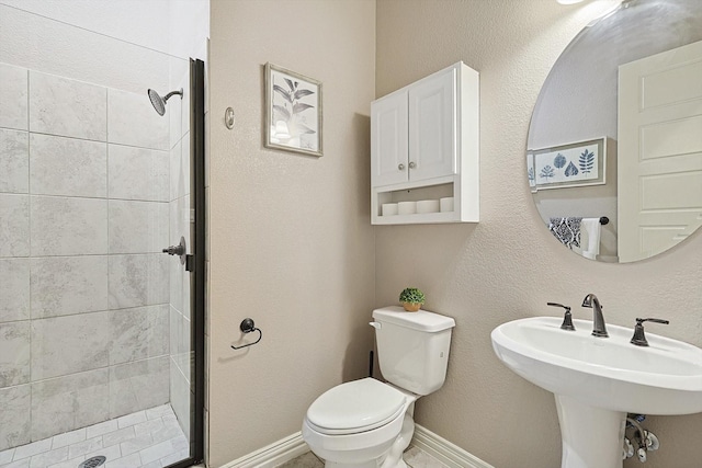 bathroom with toilet, sink, and a tile shower