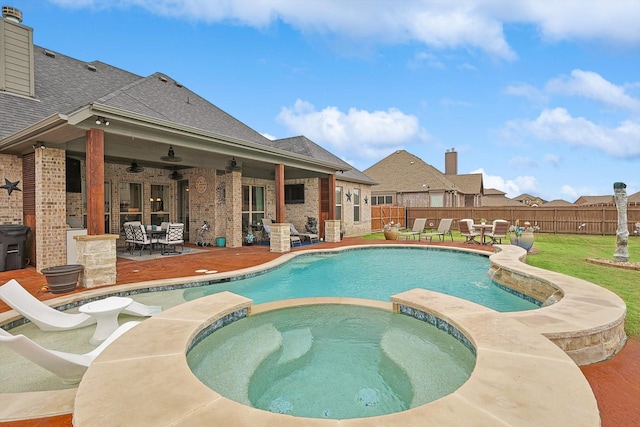 view of pool with ceiling fan, an in ground hot tub, a lawn, and a patio